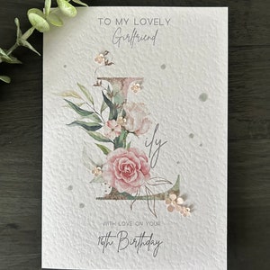 May include: A white card with a floral design and the text "To my lovely Girlfriend with love on your 16th Birthday".