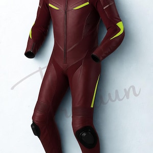 May include: A burgundy leather racing suit with neon yellow accents. The one-piece suit features a front zipper, padded knees, and black protective elements. The Traxiun logo is visible in the upper right corner.