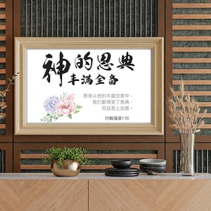 May include: A framed print with Chinese calligraphy and floral accents. The text reads "God's Grace, Full and Complete." The artwork features a light wooden frame and is displayed on a wooden cabinet with decorative elements.