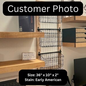 May include: A wall-mounted storage unit with three wire baskets and wooden shelves. The unit is 91 cm wide, 25 cm high, and 5 cm deep. The stain is Early American. The text "Customer Photo" is at the top.