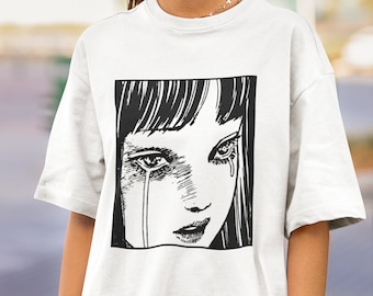 May include: White t-shirt with a black and white graphic print of a woman's face with tears streaming down her cheeks.