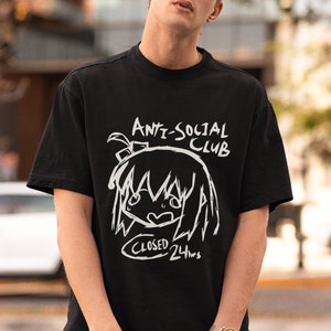 Puede incluir: Una camiseta negra con un estampado gr&aacute;fico blanco de un personaje de dibujos animados con el texto "Anti-Social Club" y "Closed 24hrs".