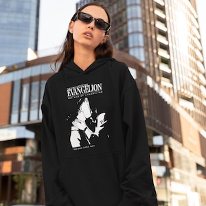 Könnte beinhalten: Schwarzer Kapuzenpullover mit dem Text "NEON GENESIS EVANGELION THE END OF EVANGELION" und einer Schwarz-Weiß-Grafik von zwei sich küssenden Figuren. Der Satz "DO YOU LOVE ME?" ist darunter gedruckt. Der Hoodie wird von einer Person mit Sonnenbrille getragen.