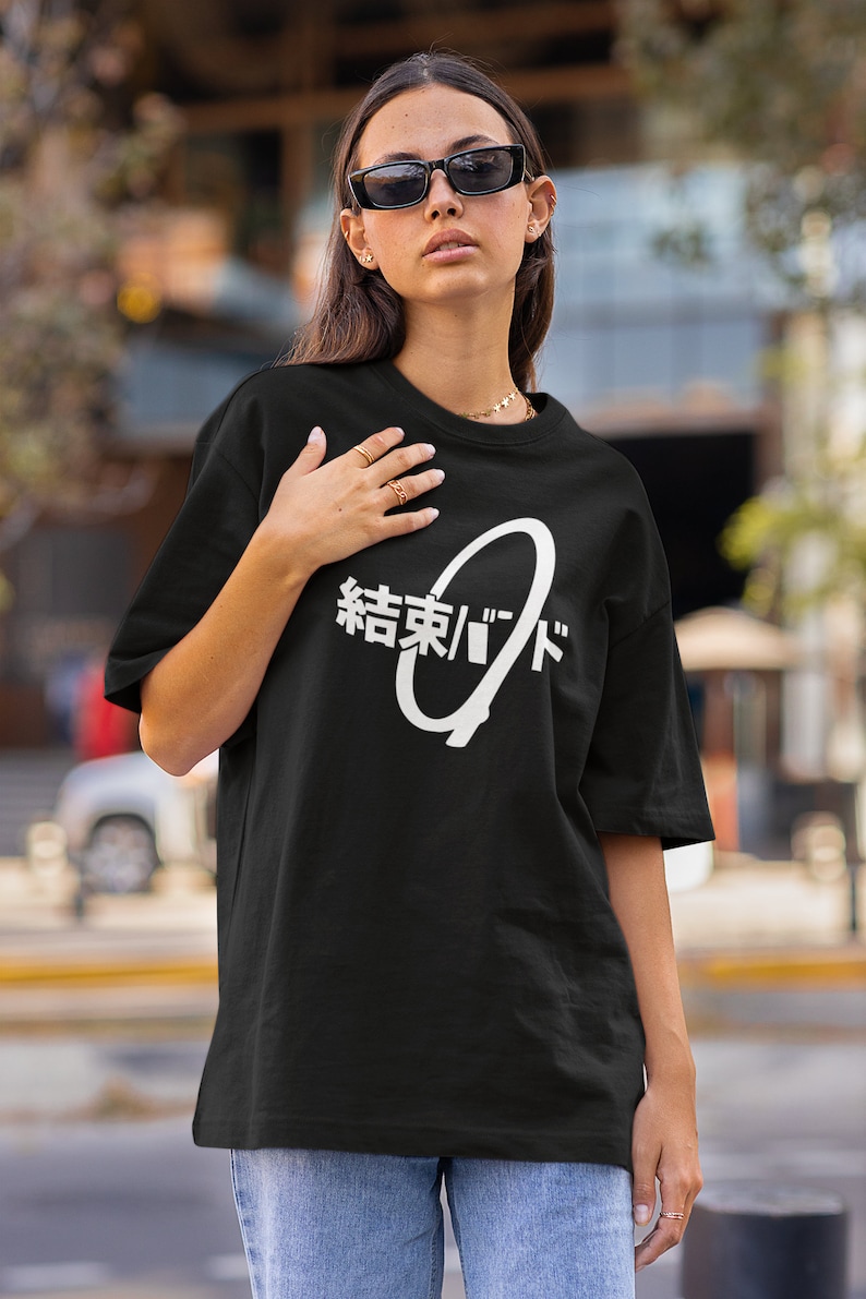 May include: A black oversized t-shirt with a white graphic design featuring a circle with the Japanese text "結末/ゴッド" (meaning "End/God").