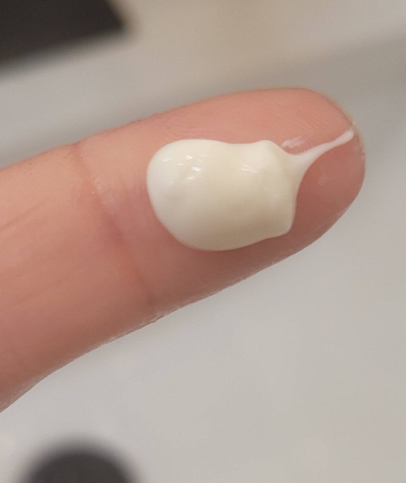 May include: A close-up of a white, creamy lotion on a fingertip.