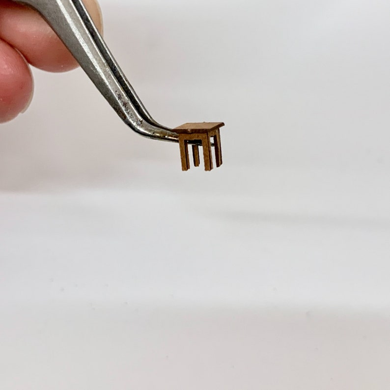 以下が含まれることがあります： 茶色の仕上げのミニチュア木製テーブル。テーブルは4本の脚と正方形の天板があります。