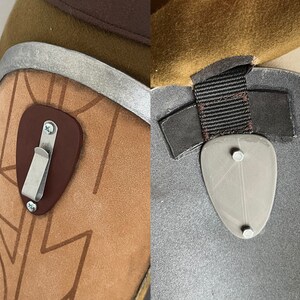 May include: Close-up of two brown leather straps with metal buckles and a gray metal plate with two screws. The straps are attached to a brown leather surface.