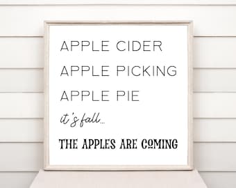 Puede incluir: Una impresión enmarcada en blanco con texto negro que dice "APPLE CIDER, APPLE PICKING, APPLE PIE, it's fall... THE APPLES ARE COMING".