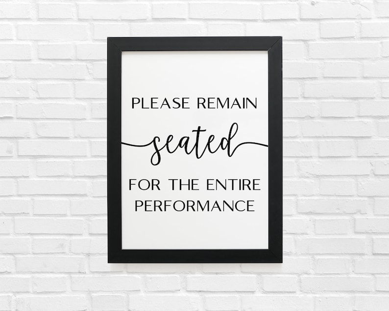 May include: Black and white sign in a black frame that reads "Please remain seated for the entire performance."