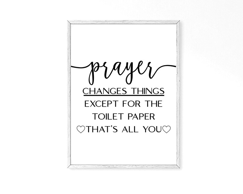 May include: A white framed print with black text that reads "prayer changes things except for the toilet paper that's all you" with two small hearts on either side of the text.
