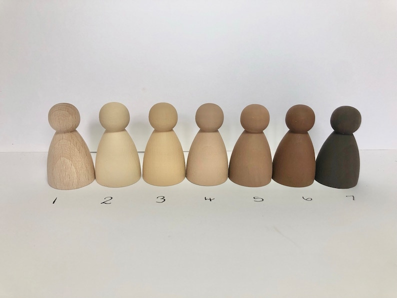 May include: Seven wooden figures in a row, painted in shades of brown, from light to dark. The figures are all the same size and shape, with a rounded head and a bell-shaped body.