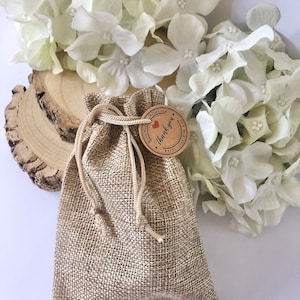 May include: A small hessian bag with a drawstring closure. The bag has a brown paper tag attached to it with the text "With Love, Thank you" and a small red heart.