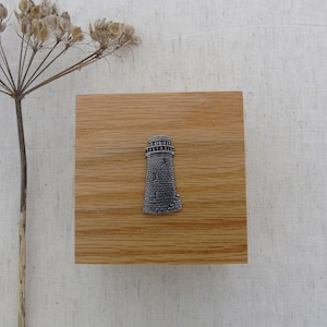 May include: A wooden box with a silver lighthouse design on the front.