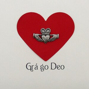 May include: A red heart with a silver Celtic knot design and the text "Gr&aacute; go Deo" on a white background.
