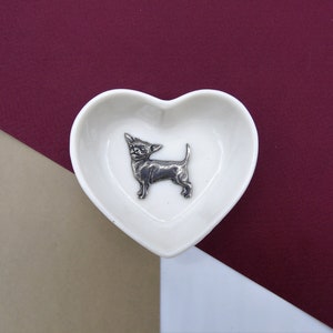 May include: White ceramic heart-shaped dish with a silver chihuahua figurine inside.