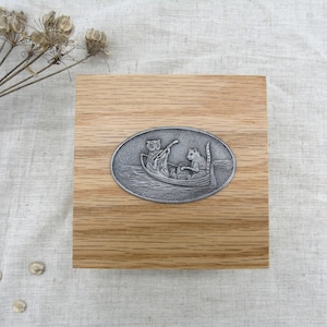 May include: A wooden box with a silver oval inlay depicting an owl and a cat in a boat. The owl is rowing the boat and the cat is sitting in the back.