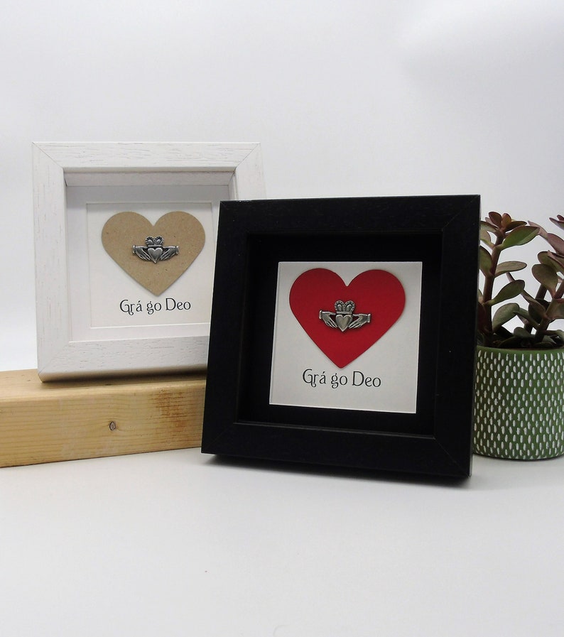 May include: Two framed pictures with a heart and a Claddagh ring. The heart is brown in one frame and red in the other. Both frames have the text "Gr&aacute; go Deo" which is Irish for "Love forever".