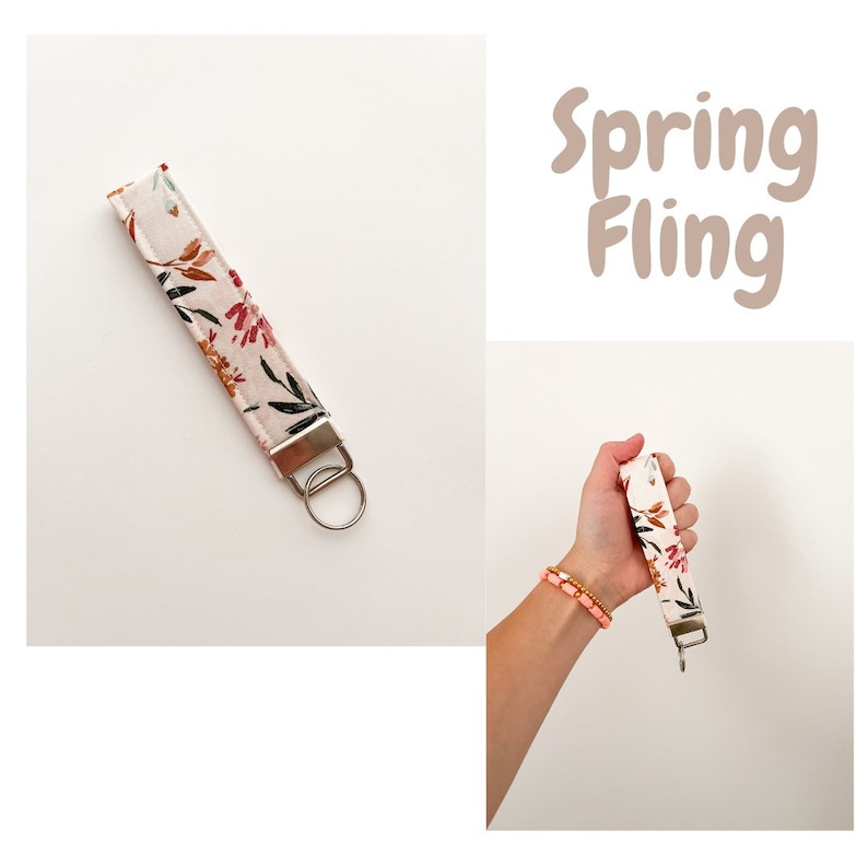 May include: A white key chain with a floral pattern and a silver key ring. The key chain has the text "Spring Fling" on it.