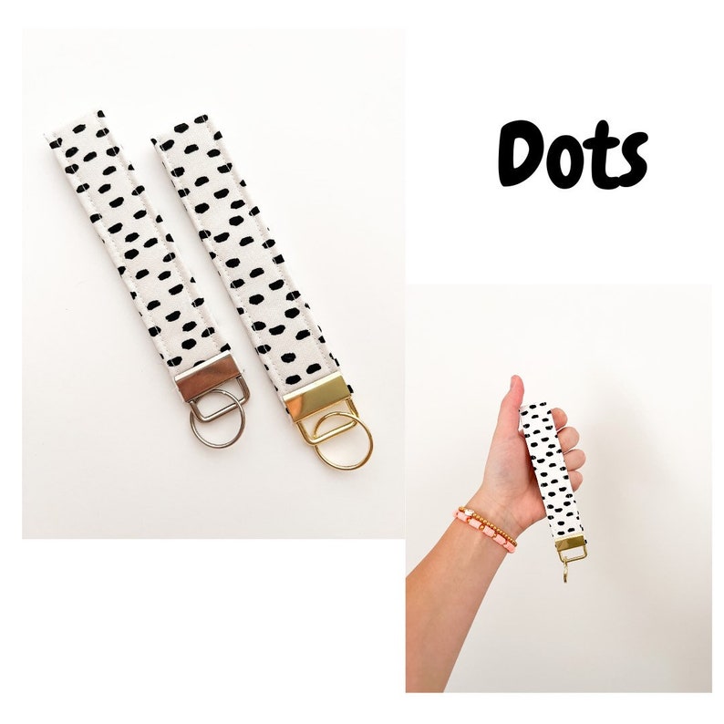 May include: Two white and black polka dot keychains with gold key rings. The keychains are made of fabric and have a black and white polka dot pattern. The word "Dots" is written in black text on a white background.