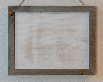 May include: A rustic wooden frame with a whitewashed finish hangs from a twine rope. The frame is empty and ready for a photo or artwork.