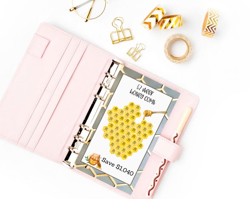 May include: A pink planner with a 57 week honey comb savings chart. The chart is a honeycomb design with the number 10 in each cell. The chart is labeled "57 week honey comb" and "Save $1,040".