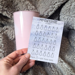 May include: A white sheet with a silver glitter background and black outline Christmas tree stickers. The sheet has the text "My Christmas Fund" and "Each = £20 Total: £600".