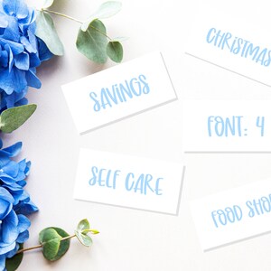 May include: White cards with blue text on a white background. The text on the cards reads "Christmas", "Savings", "Self Care", "Font: 4", and "Food Shop". Blue hydrangeas and eucalyptus leaves are on the left side of the image.