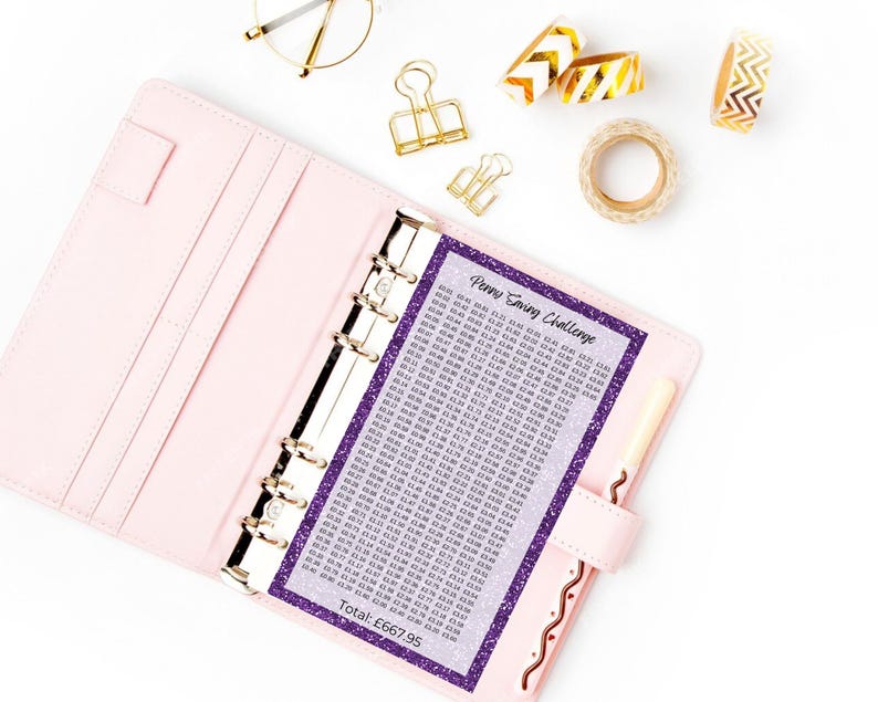 May include: A light pink six-ring binder containing a purple glitter-bordered Penny Saving Challenge tracker sheet with a grid of monetary values and the text Total: &pound;667.95. The binder is accompanied by gold binder clips and gold patterned tape.