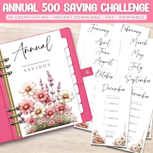 以下が含まれることがあります： ピンク色のA6バインダー。花柄のデザインと貯蓄トラッカーのインサートが付いています。「年間貯蓄」と「年間500貯蓄チャレンジ」の文字があります。インサートには月と貯蓄目標が記載されています。