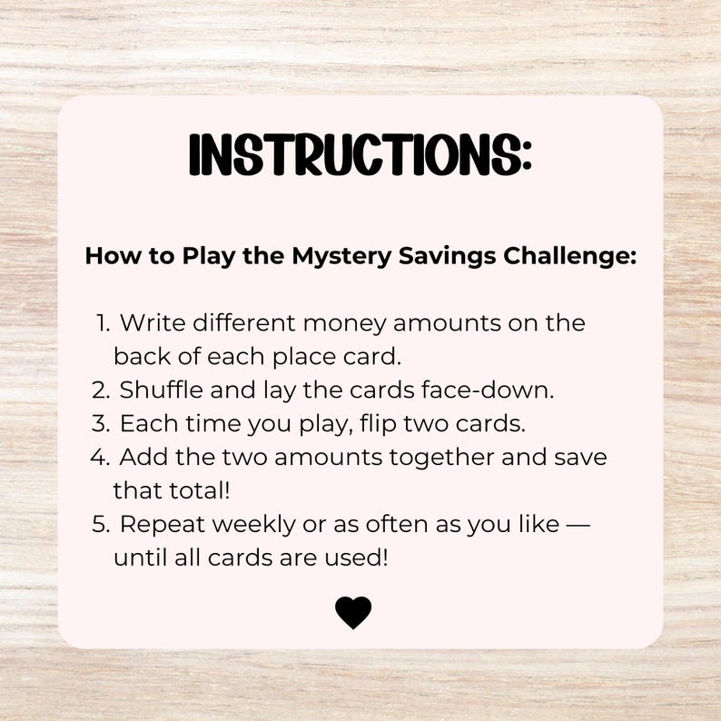Op de afbeelding: Een lichtroze vierkante kaart met afgeronde hoeken en zwarte tekst: INSTRUCTIONS: How to Play the Mystery Savings Challenge: 1. Write different money amounts on the back of each place card. 2. Shuffle and lay the cards face-down. 3. Each time you play, flip two cards. 4. Add the two amounts together and save that total! 5. Repeat weekly or as often as you like &mdash; until all cards are used! Een klein zwart hartje staat onderaan.