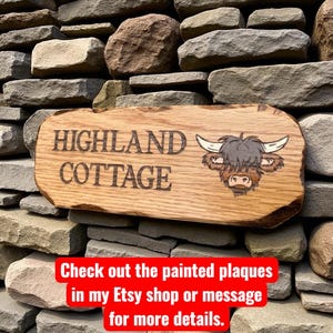 Pode incluir: Placa de madeira com a inscri&ccedil;&atilde;o "HIGHLAND COTTAGE" e uma ilustra&ccedil;&atilde;o de uma vaca Highland. A placa est&aacute; montada numa parede de pedra. A madeira tem um acabamento natural. O texto "Check out the painted plaques" tamb&eacute;m &eacute; vis&iacute;vel.