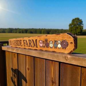 May include: A rectangular wooden sign with a natural live edge featuring the text BRAESIDE FARM in black lettering followed by a series of seven colorful cartoon animal illustrations including a pig, rabbit, llama, sheep, goat, and cow.