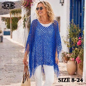 May include: A woman wearing a blue, open-weave poncho with fringe. The poncho is over a white top and white pants. The image includes the text "SIZE 8-24" and the logo "JCUK".