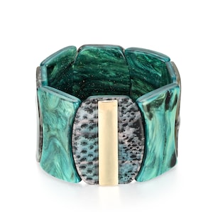 May include: A green and black patterned bangle bracelet with a gold metal accent. The bracelet is made of resin and has a chunky, bold design.