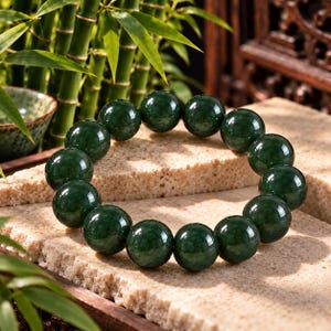 May include: A circular bracelet composed of smooth, polished, dark green spherical beads. The beads are uniform in size and strung together to form a continuous loop, showcasing a deep, translucent emerald hue with subtle internal variations.