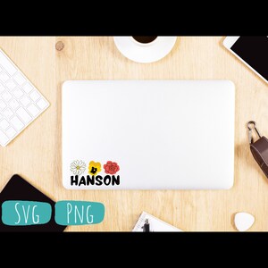 May include: A white laptop with a sticker on it. The sticker has three flowers and the word "HANSON" in black letters.