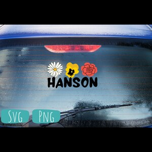 May include: A car window decal with three flowers and the word "HANSON" in black lettering. The flowers are a white daisy, a yellow pansy, and a red rose.