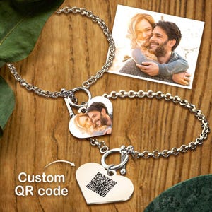 May include: Two silver-toned bracelets with heart-shaped pendants. One pendant features a custom QR code, the other two display a photo of a couple. The bracelets are linked together. The words "Custom QR code" are printed on the image.