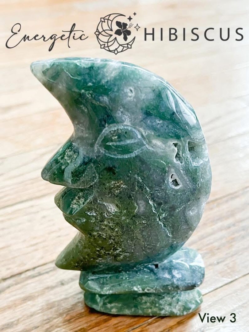 May include: Green agate crescent moon carving with a textured surface. The carving is on a wooden surface. View 3.