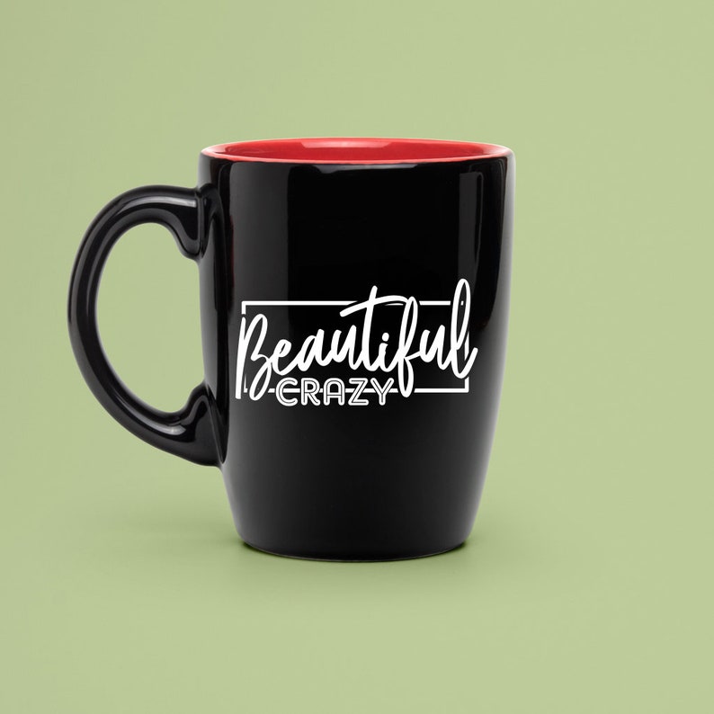 May include: Black ceramic coffee mug with a red rim. The mug has white text that reads "Beautiful -CRAZY-" in a rectangular box.