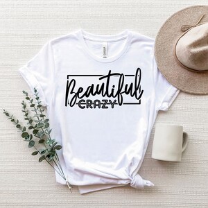 May include: White t-shirt with black text that reads "Beautiful - Crazy" in a rectangle.