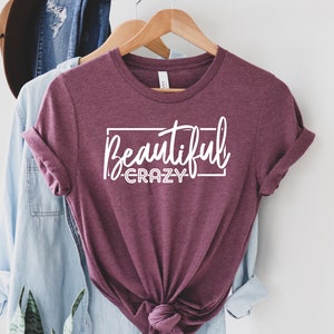 May include: A maroon t-shirt with the text "Beautiful Crazy" in white lettering inside a white rectangle.