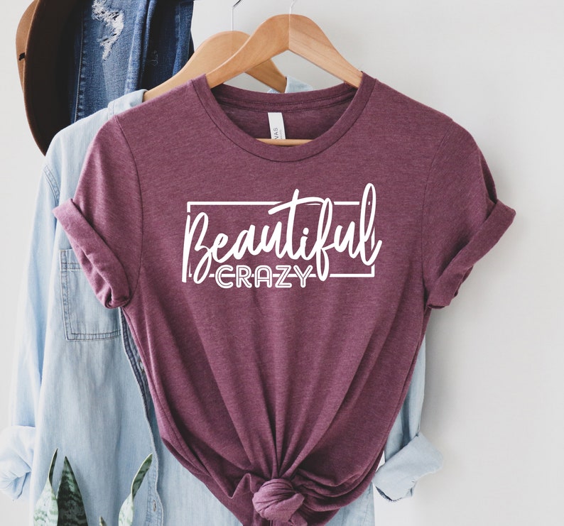 May include: A maroon t-shirt with the text "Beautiful Crazy" in white lettering inside a white rectangle.