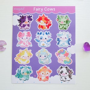 Puede incluir: Una hoja de pegatinas con 12 dise&ntilde;os diferentes de vacas hadas. Cada vaca tiene un esquema de color diferente y caracter&iacute;sticas &uacute;nicas, como alas, cuernos y flores. Las pegatinas est&aacute;n impresas sobre un fondo morado con nubes blancas.