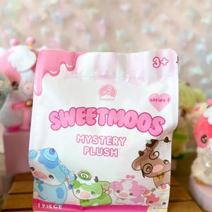 May include: A white and pink Sweetmoos Mystery Plush bag featuring cartoon cow illustrations. The bag has a pink drip design at the top and the text "Sweetmoos" and "Mystery Plush". The bag is marked "1 Piece" and "3+".