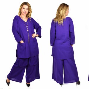May include: A purple long-sleeved tunic top with a v-neck and two pockets, paired with matching wide-leg pants. The outfit is made of a soft, flowing fabric.