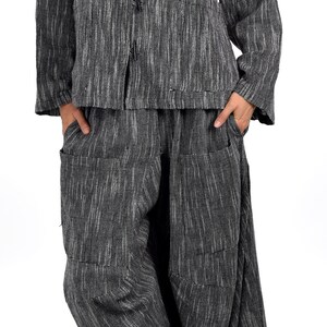 May include: A black and white striped linen jacket with a mandarin collar and a button closure. The jacket is paired with matching black and white striped linen pants.