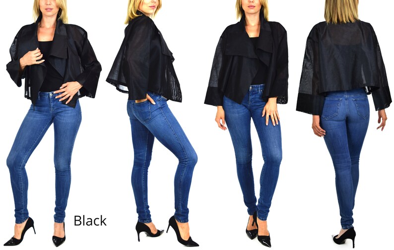 May include: A black cropped jacket with a draped collar and sheer sleeves. The jacket is worn over a pair of blue jeans.