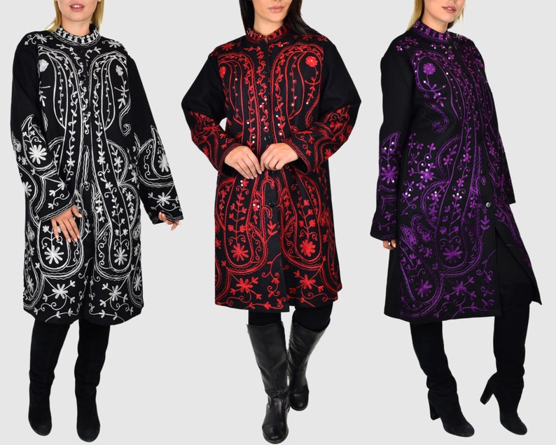 May include: Three long embroidered coats in black, red, and purple. The coats feature intricate floral and paisley patterns. Each coat has a mandarin collar and button closures. The models are wearing black leggings and boots.