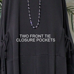 May include: Black long-sleeved tunic with two front tie closure pockets. The text "TWO FRONT TIE CLOSURE POCKETS" is printed on the front of the tunic.